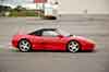 photograph of a red ferrari f355 berlinetta convertible from the side in a parking lot amherst ny